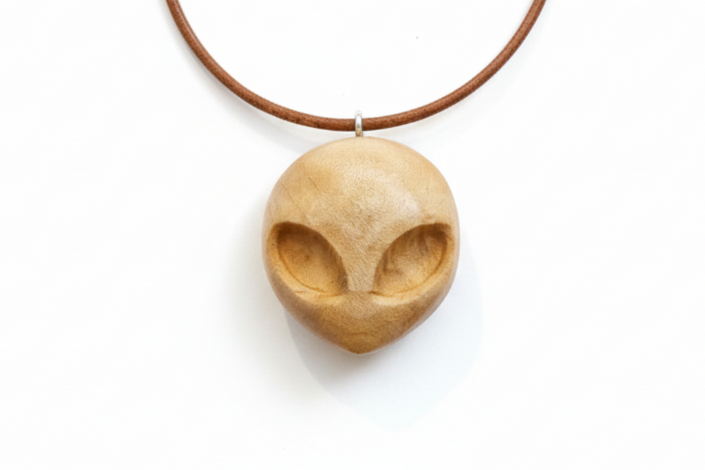 Alien pendant carved from silver maple wood with a brown cord