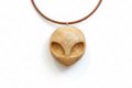 Alien pendant carved from silver maple wood with a brown cord