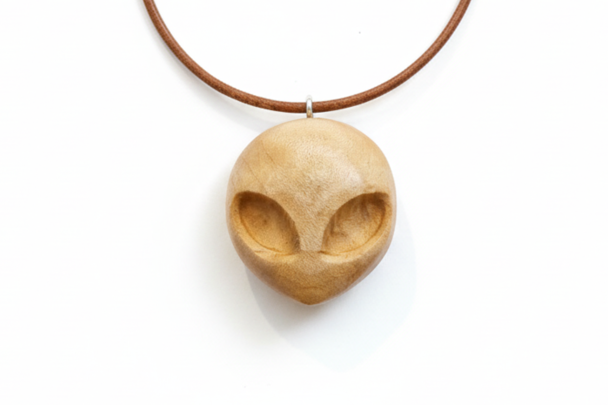 Alien pendant carved from silver maple wood with a brown cord
