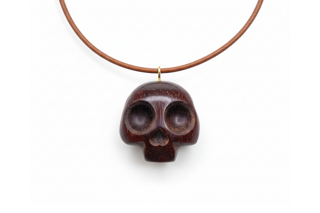 Close-up of carved wengé wood skull pendant showing natural wood grain and polished finish