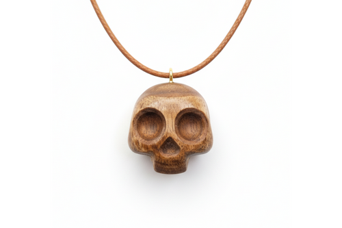 Handcrafted dark walnut wood skull pendant on leather cord against white background