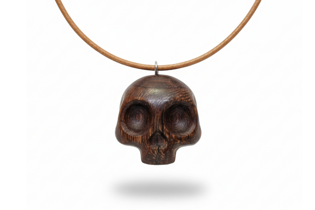 Handcrafted wengé skull pendant with dark brown wood grain and natural finish on white background