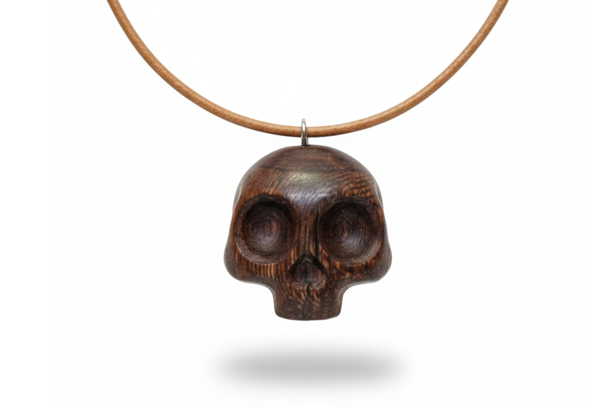 Handcrafted wengé skull pendant with dark brown wood grain and natural finish on white background