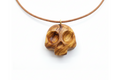 Olive wood skull pendant with warm golden tones and swirling grain on leather cord against white background