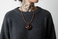Wengé wood skull pendant worn by model in dark sweater showing size and styling