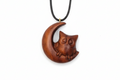 Wooden owl pendant on a crescent moon with a black cord against a white background